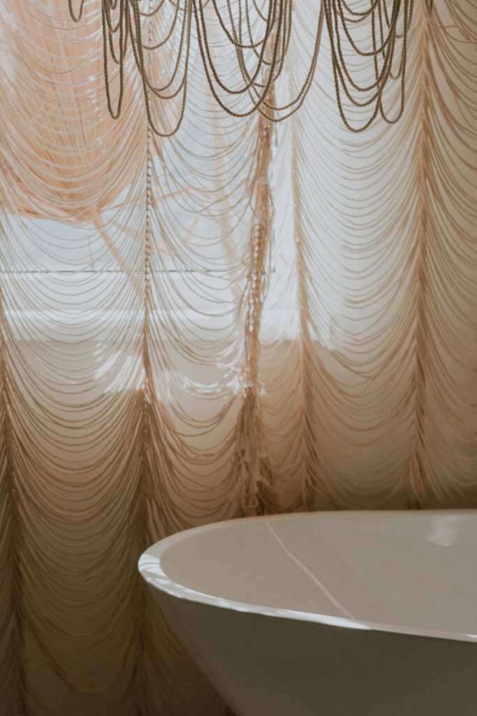 A serene bathroom with stylish draped curtains and a modern bathtub.